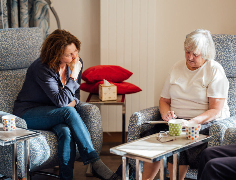 Two people sit together on comfy chairs in the Living Well Centre