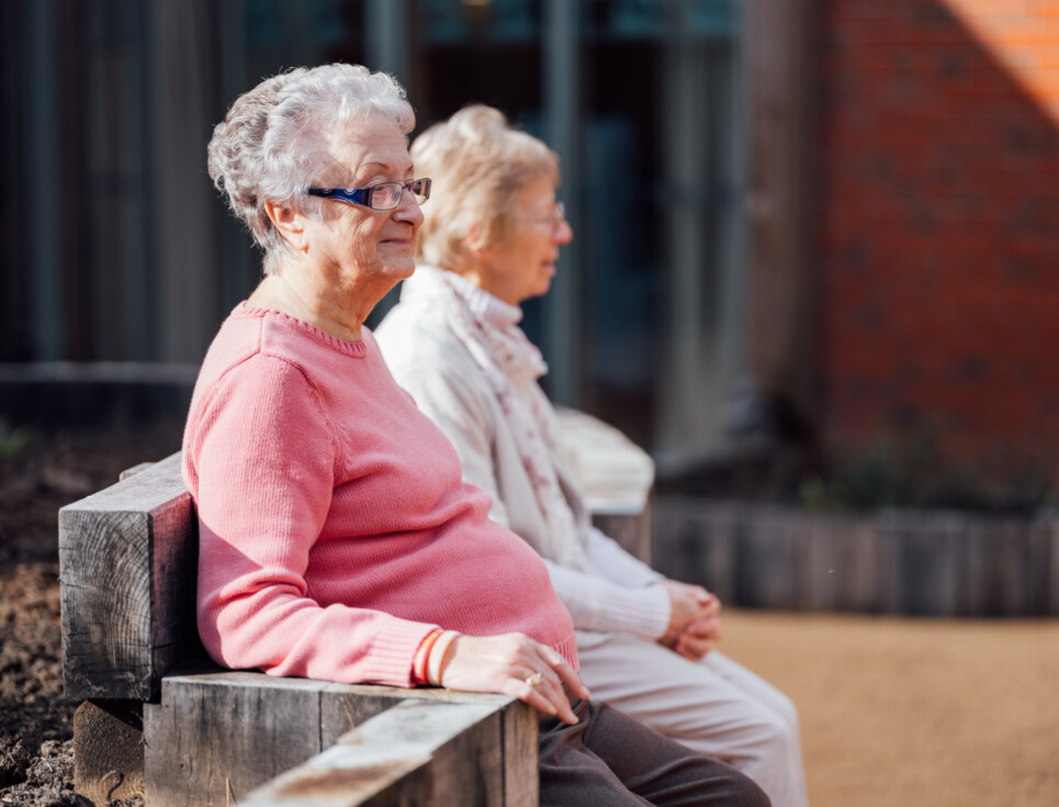 Two people sit on a bench in the hospice's garden